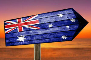 Iconic Foods to Try in Australia 5 A wooden arrow sign painted with the Australian flag points to the right against a sunset background.