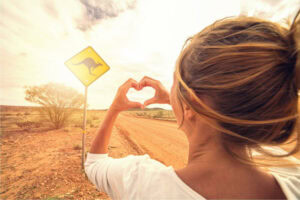 20 Places to Experience the Australian Outback 2 A woman standing by a dirt road making a heart with her hands in the Australian Outback