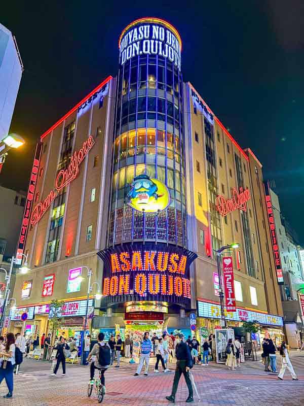 Tokyo Free Walking Tours: 3 Tours I Tried and Recommend 9 Colorful Don Quijote store in Asakusa, Tokyo, illuminated at night with neon signs and people walking in front of the entrance.