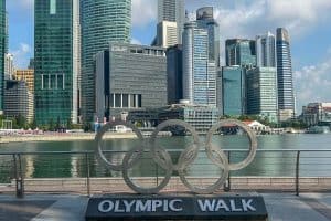 2 Day Singapore Itinerary - Best Things to Do in 48 Hours 34 Large Olympic rings sculpture with "Olympic Walk" sign in front of a waterfront and modern skyscrapers—a must-see spot on any 2 Day Singapore Itinerary.