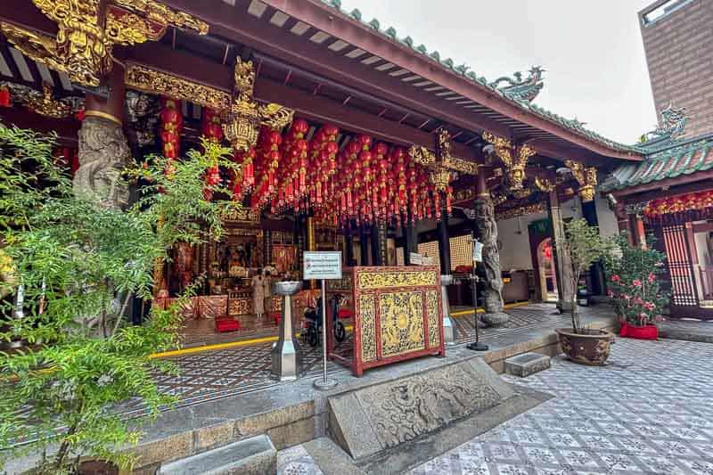 A traditional Chinese temple with ornate gold decorations, red lanterns hanging from the ceiling, and stone carvings at the entrance—a must-see if you’re wondering how many days in Singapore you need to explore its rich culture.