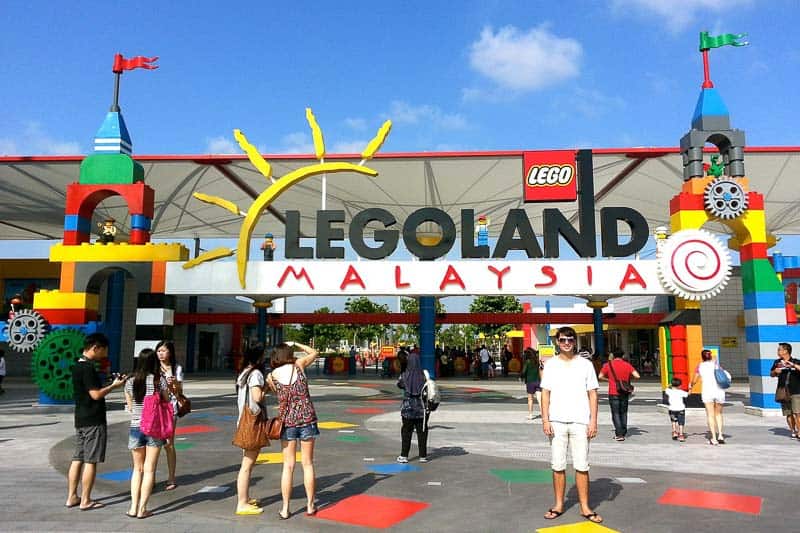 The entrance of LEGOLAND Malaysia, featuring colorful LEGO-themed structures, the park logo, and visitors standing and walking around.