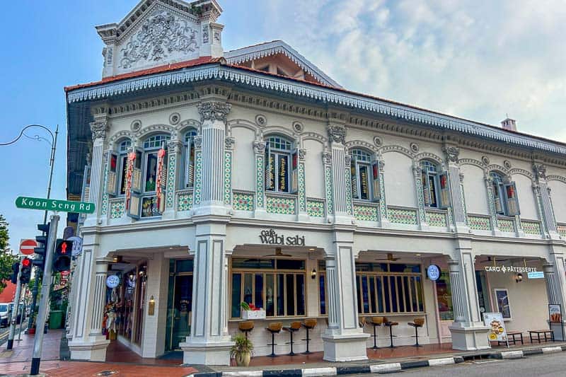 Best Areas to Stay in Singapore 9 A two-story white heritage shophouse with ornate details houses Café Wabi Sabi and Carrotsticks & Cravings on a street corner at Koon Seng Road.