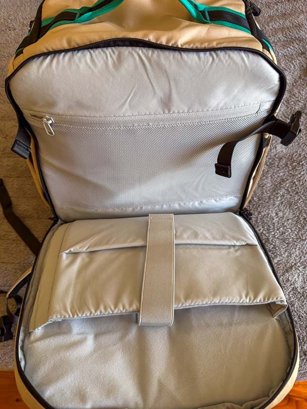 BAGSMART BLAST Series Review: Tested on My Travels 7 An open Blast 40L Rucksack lies on the floor, revealing a padded interior with a mesh zip pocket on the upper flap and a large padded compartment with a securing strap on the lower section.